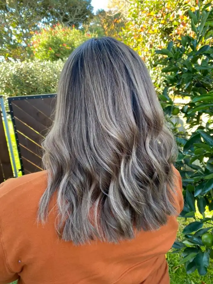 Outdoor back view of cool ash balayage on long wavy hair