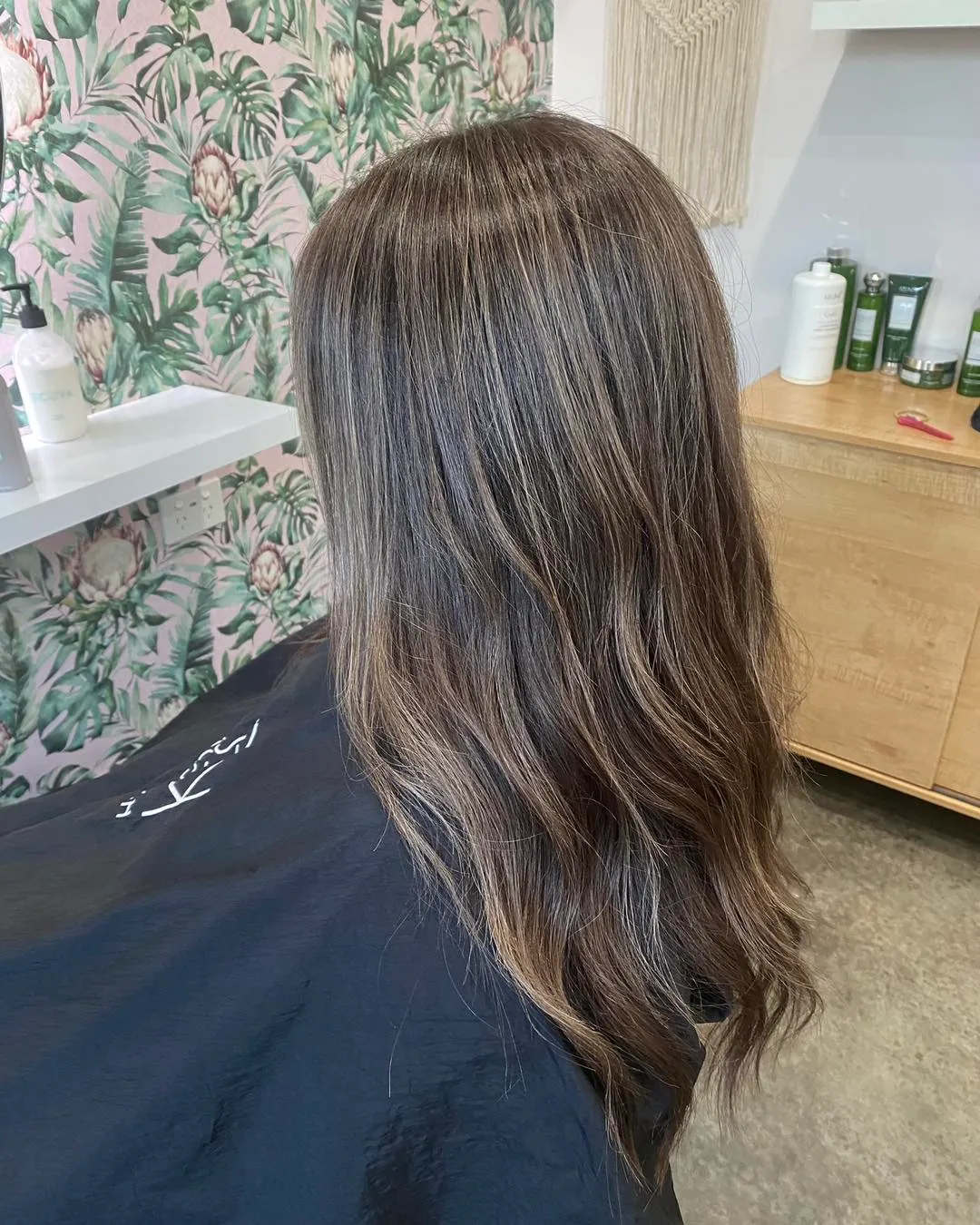 Back view of long cool ash brunette with subtle balayage waves
