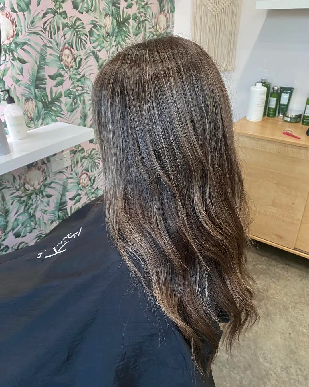 Back view of long cool ash brunette with subtle balayage waves