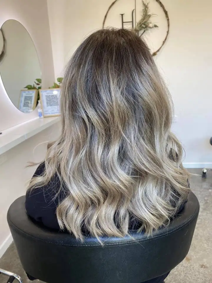 Back view of long lived-in blonde balayage with smoky root and beachy waves