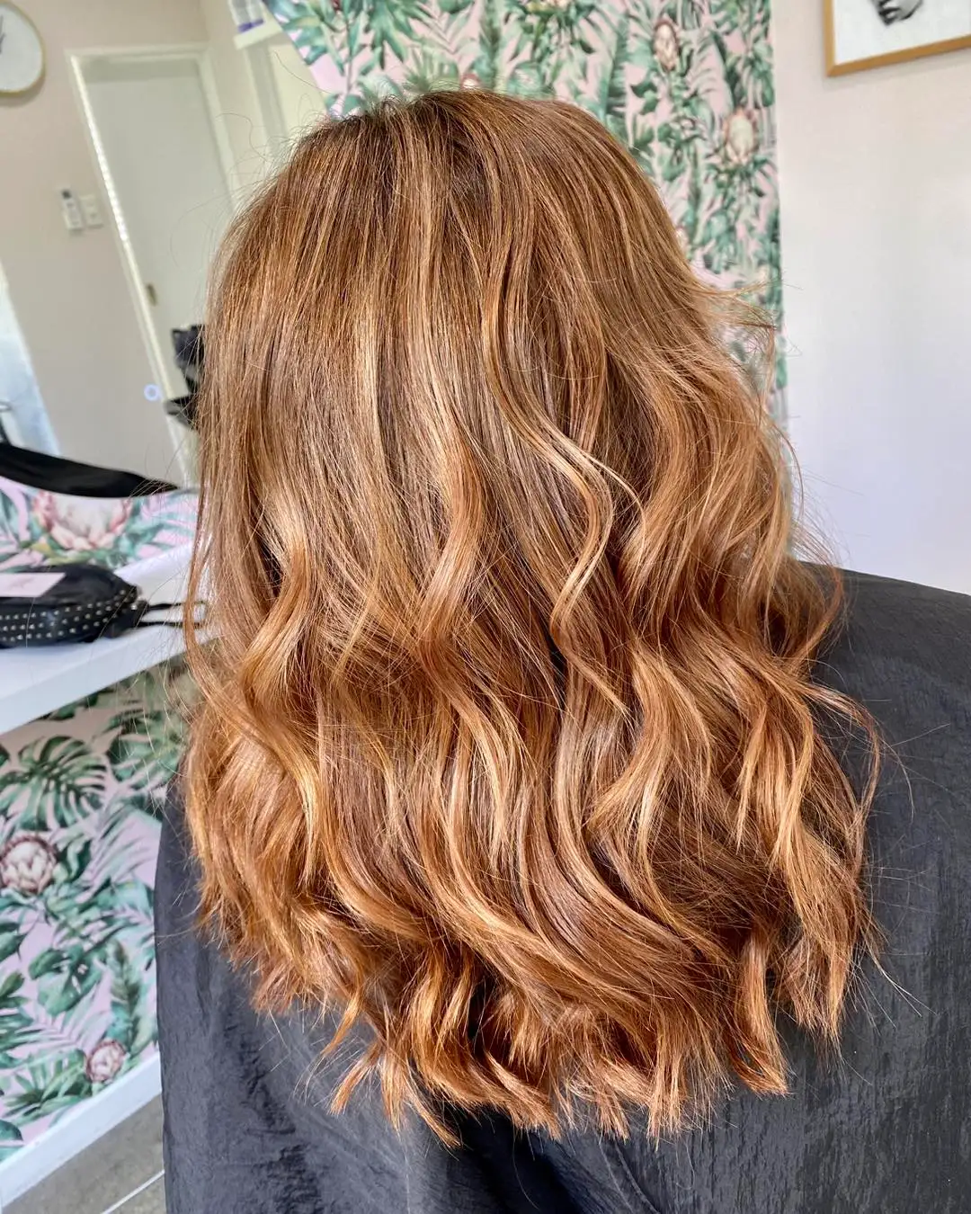 Side back view of long warm caramel waves with honey lights